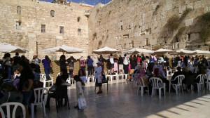 At the Western Wall, women lean over the barrier to the mens' side to see their sons' bar mitzvahs.