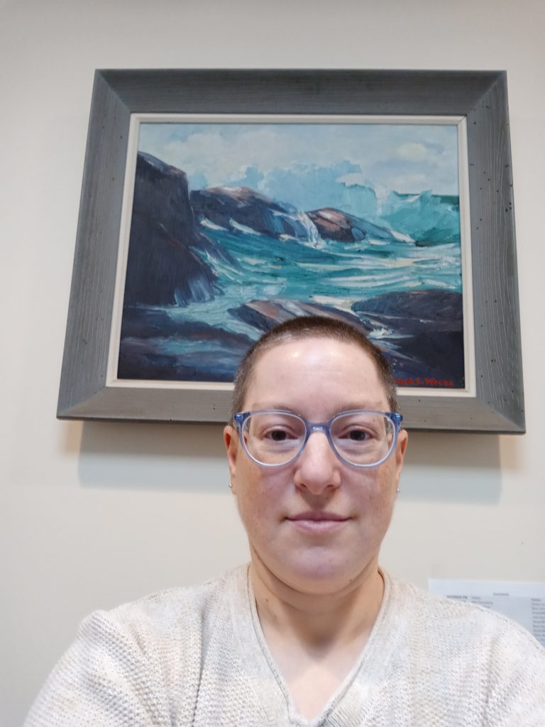 Image of Ellen L. Weene in front of a framed seascape oil painting made by her paternal grandfather, Joseph L. Weene